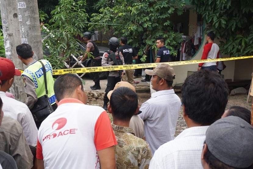 Petugas kepolisian bersenjata lengkap berjaga di rumah pelaku teror polisi saat dilakukan penggeledahan, di Sepatan, Kabupaten Tangerang, Banten, Kamis (20/10). 