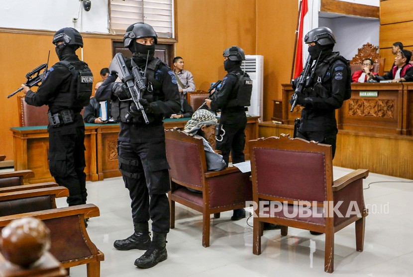 Petugas kepolisian bersenjata lengkap menjaga terdakwa kasus dugaan serangan teror bom Thamrin dengan terdakwa Oman Rochman alias Aman Abdurrahman saat menjalani sidang lanjutan di Pengadilan Negeri Jakarta Selatan, Jumat (25/5). 