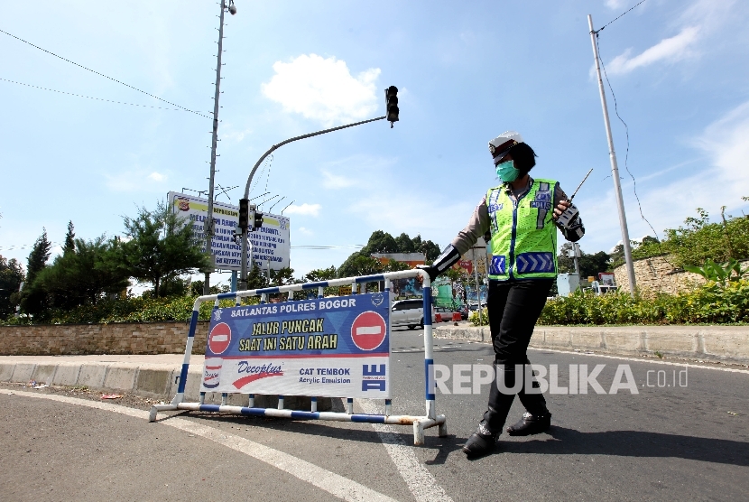 Petugas kepolisian bersiap untuk melakukan rekayasa lalulintas untuk mencegah kemacetan kendaraan menuju puncak yang terjebak kemacetan di Simpang Gadog, Bogor, Jawa Barat, Jumat (6/5).  (Republika/Rakhmawaty La'lang)