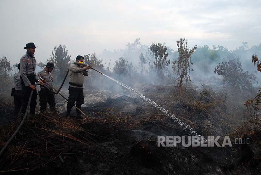 Petugas Kepolisian berusaha memadamkan kebakaran lahan gambut di Desa Rimbo Panjang, Kabupaten Kampar, Riau,