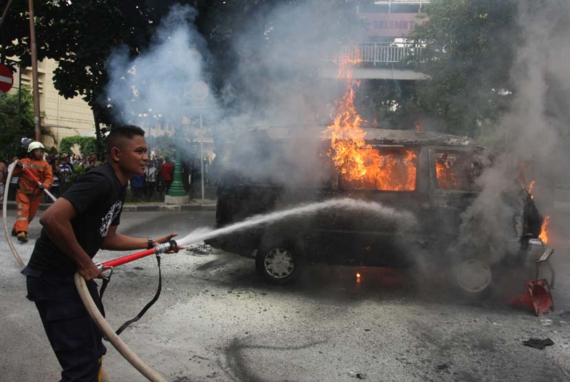 Petugas Kepolisian berusaha memadamkan sebuah mobil dengan nopol B 2791 AJ yang terbakar di depan Mabes Polri, Jakarta, Rabu (4/2). (ANTARA/Reno Esni)