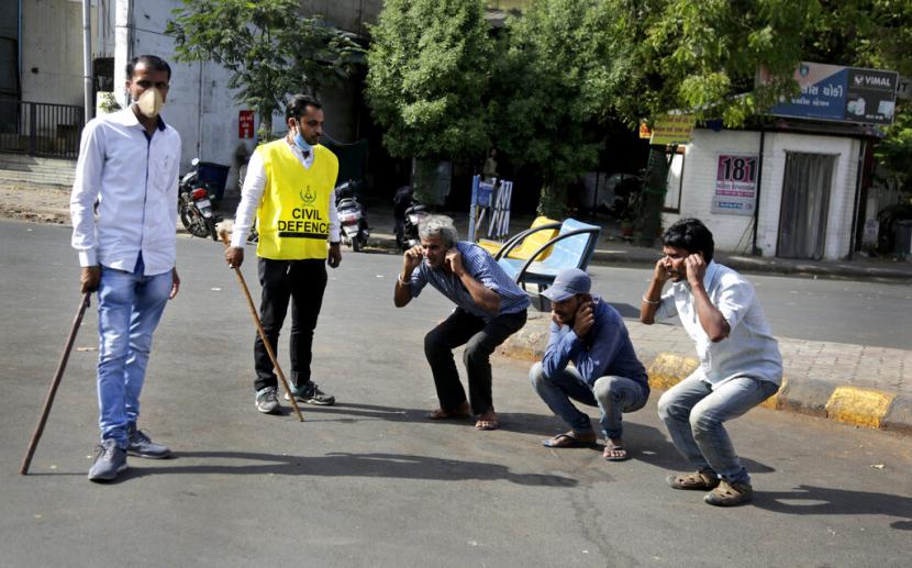 Petugas kepolisian India menghukum pelanggar kebijakan lockdown di Ahmeddabad, India, Selasa (24/3). Mereka diminta melakukan sit up sambil memegang kuping. India sudah memberlakukan lockdown sejak kasus positif corona melonjak di sana.