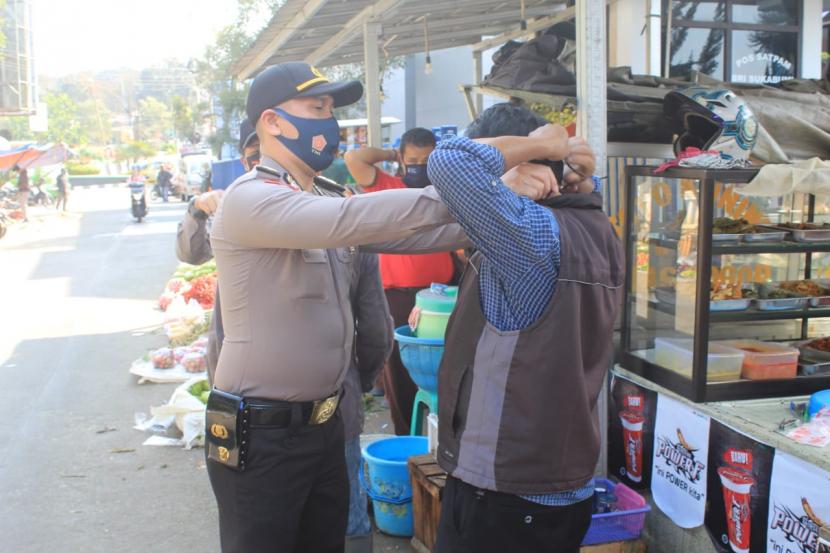 Petugas kepolisian kota Sukabumi sedang memasangkan masker pada salah seorang pedagang di pasar kota Sukabumi (ilustrasi)