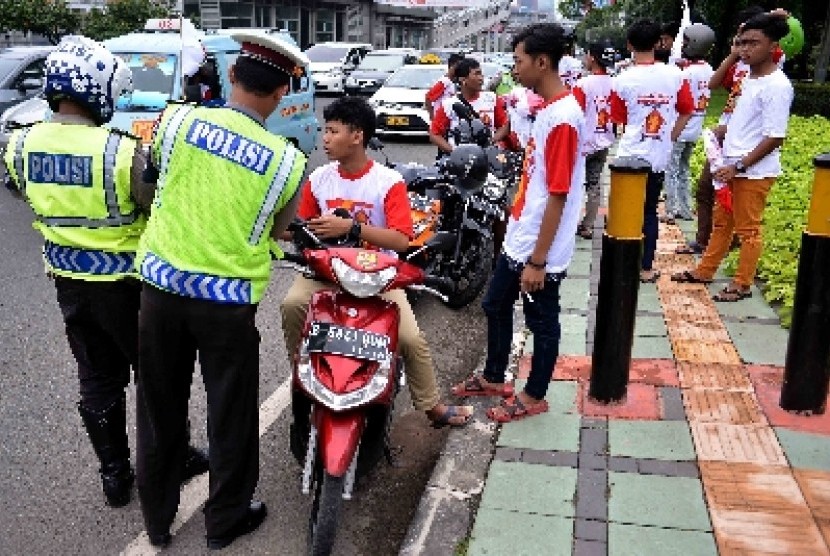 Petugas kepolisian lalu lintas menilang simpatisan partai saat kampanye di kawasan Gatot Subroto, Jakarta.