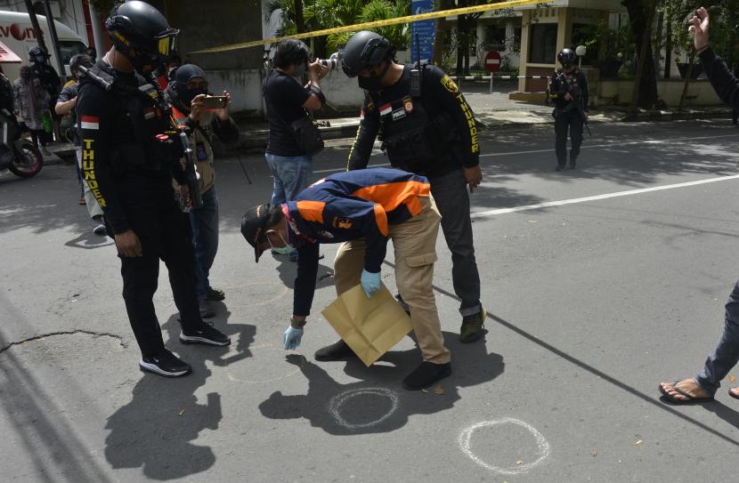 Police officers conduct an investigation around the remains of the explosion of the alleged suicide bombing in front of the Catholic Church in the Cathedral, Makassar, South Sulawesi, Sunday (28/3/2021). The bomb explosion at the church resulted in a death of two of the suspected suicide bombers and injuring 14 congregants and church officials