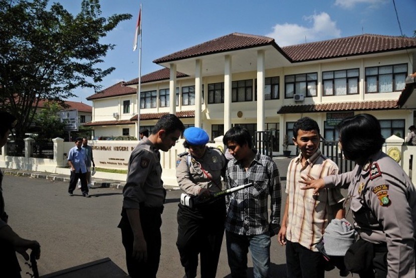 Petugas kepolisian melakukan pemeriksaan terhadap pengunjung saat digelar sidang teroris bom Beji di Pengadilan Negeri kota Depok, Jawa Barat, Senin (24/6). Pengamanan tersebut untuk mengantisipasi kejadian yang tidak diinginkan saat vonis bagi terdakwa Ag