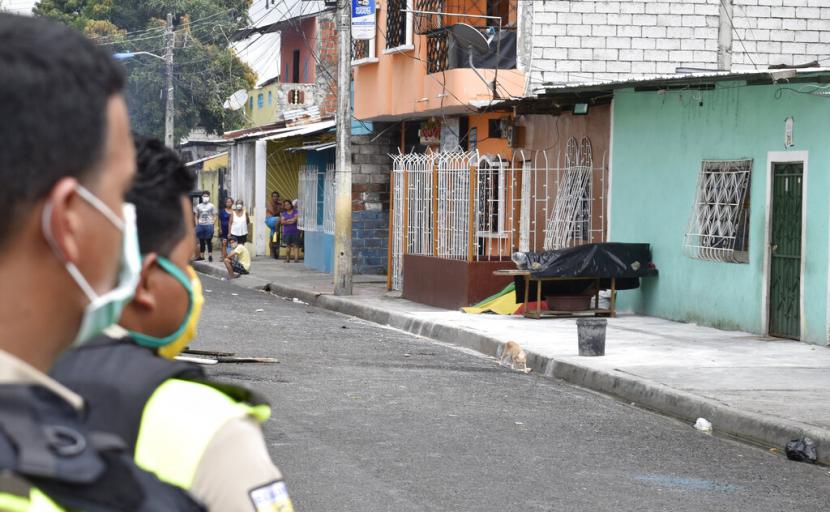 Petugas kepolisian melihat jenazah terduga Covid-19 yang ditutup plastik di teras perumahan di kawasan pinggiran Guayaquil, Ekuador, Sabtu (4/4). RS menolak pasien dan jenazah dibiarkan di tepi jalan selama berhari-hari sana.