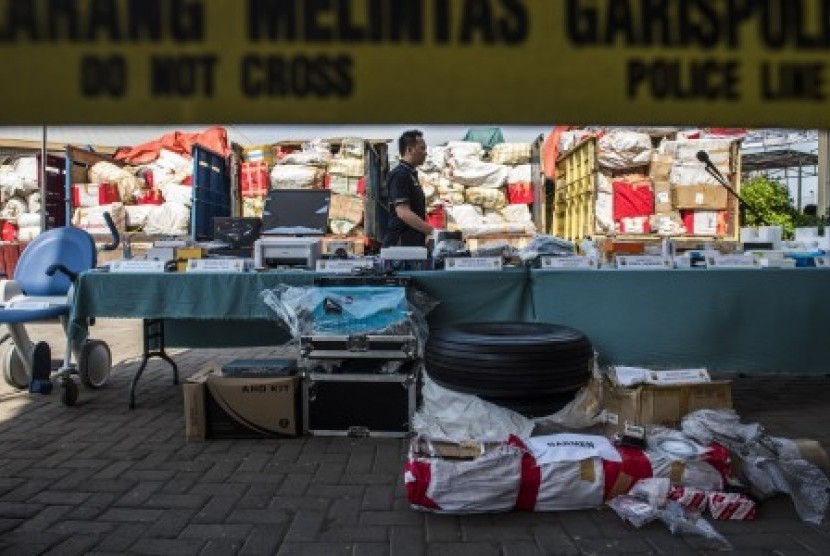 Petugas Kepolisian melintas diantara barang impor selundupan saat gelar barang bukti di Polres Pelabuhan Tanjung Priok, Jakarta Utara, Senin (23/11).