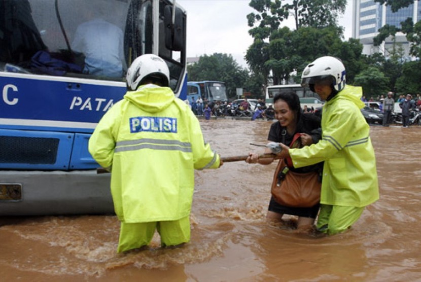  Petugas Kepolisian membantu seorang perempuan yang mencoba melintasi banjir yang merendam di kawasan Tosari Jakarta Pusat, Kamis (17/1).