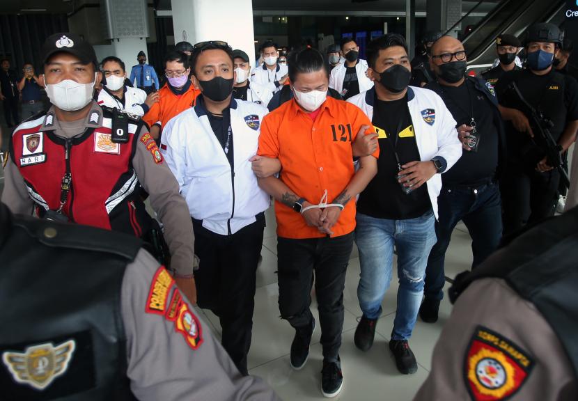 Petugas kepolisian membawa tersangka bandar besar judi online jaringan Jakarta Elvan Adrian (tengah) setibanya dari Kamboja di Bandara Soekarno Hatta, Tangerang, Banten, Sabtu (15/10/2022).
