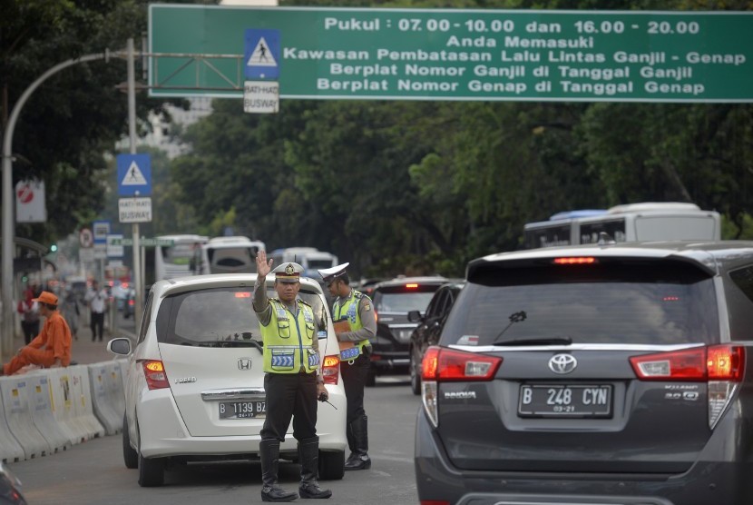 Petugas Kepolisian memberhentikan kendaraan dan memberikan imbauan kepada pengendara berplat nomor genap saat melintas di Kawasan Pembatasan Lalu Lintas Ganjil Genap, Medan Merdeka Barat, Jakarta, Jumat (26/8).