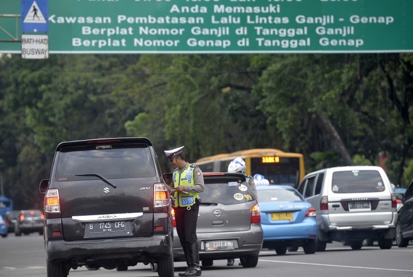 Petugas Kepolisian memberhentikan kendaraan dan memberikan imbauan kepada pengendara berpelat nomor genap saat melintas di kawasan pembatasan lalu lintas ganjil-genap, Medan Merdeka Barat, Jakarta, Jumat (26/8). 