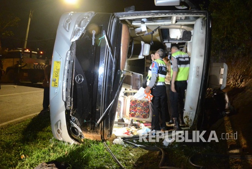 Petugas kepolisian memeriksa bis saat evakuasi kecelakaan bus pariwisata di tanjakan Emen, Kabupaten Subang, Sabtu (10/2).