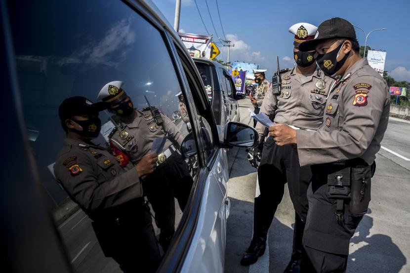 Petugas kepolisian memeriksa identitas dan surat keterangan sehat dari pengemudi kendaraan dengan pelat nomor luar Bandung saat operasi ppkm mikro di gerbang keluar Tol Soreang, Kabupaten Bandung.