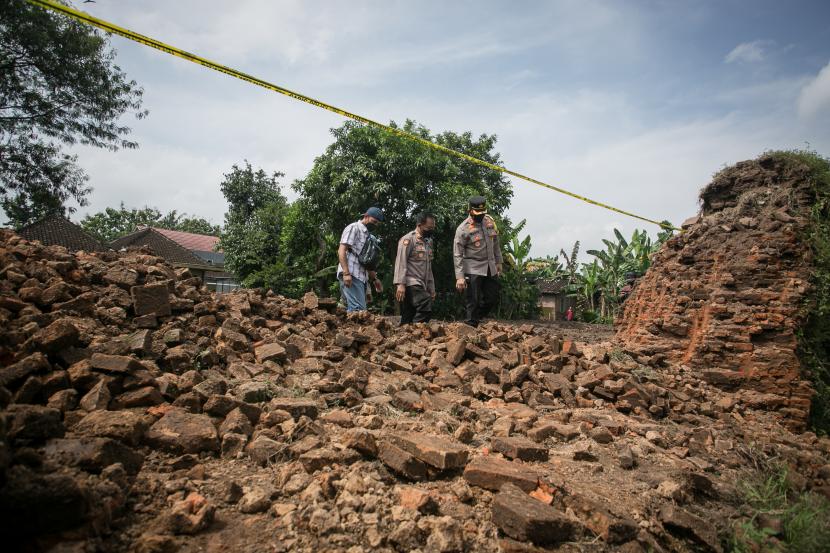 Petugas kepolisian memeriksa kondisi tembok benteng Keraton Kartasura yang rusak dijebol warga di Sukoharjo, Jawa Tengah, Sabtu (23/4/2022). Ganjar mengatakan perusakan tembok Keraton Kartasura jadi peringatan untuk pemerintah.