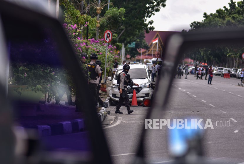 Petugas kepolisian memeriksa mobil minibus yang digunakan pelaku teror untuk menyerang Polda Riau, di Pekanbaru, Riau, Rabu (16/5).