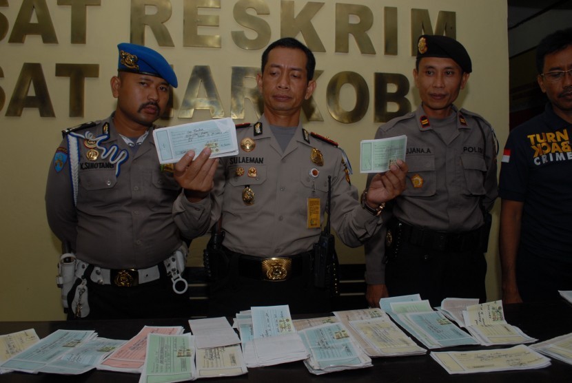 Petugas kepolisian memperlihatkan lembaran kuitansi sebagai barang bukti dugaan penipuan ratusan pencari kerja yang dijanjikan disalurkan ke PT Semen Jawa di Polres Sukabumi Kota, Sukabumi, Jawa Barat, Selasa (2/3) malam.