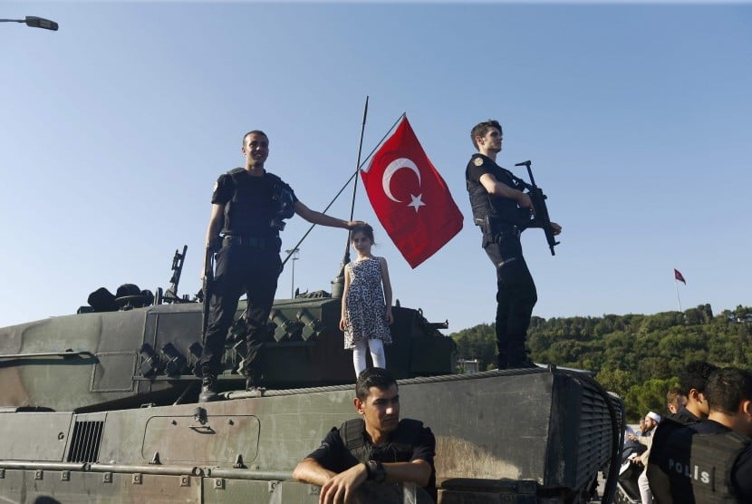 Petugas kepolisian menduduki kendaraan militer yang digunakan kudeta, setelah sejumlah personel militer pro-kudeta menyerahkan diri di Jembatan Bosphorus Istanbul, Sabtu (16/7).