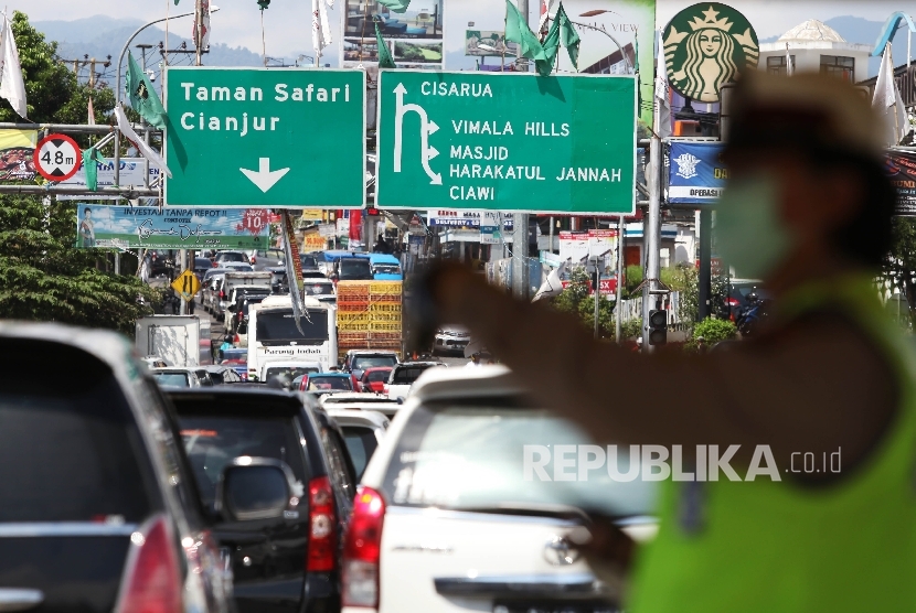  Petugas kepolisian mengatur kendaraan menuju puncak yang terjebak kemacetan di Simpang Gadog, Bogor, Jawa Barat, Jumat (6/5). (Republika/Rakhmawaty La'lang)