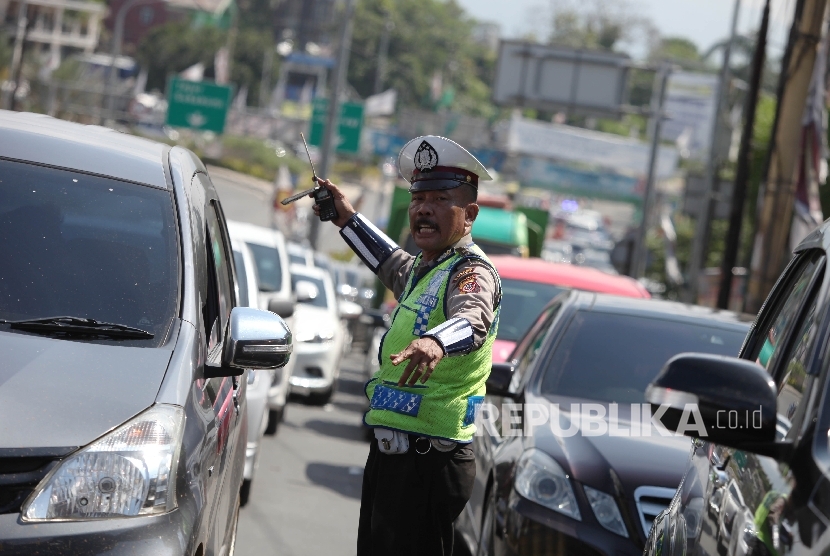 Petugas kepolisian mengatur kendaraan menuju puncak yang terjebak kemacetan di Simpang Gadog, Bogor, Jawa Barat, Jumat (6/5).  (Republika/Rakhmawaty La'lang)