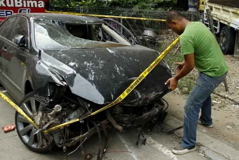 Petugas kepolisian mengecek kondisi mobil Camry bernopol B 1596 KF yang ringsek di Halaman Pos Polisi Ring Road, Jagakarra, Jakarta Selatan, Ahad (31/3).