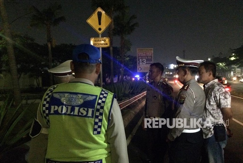 Petugas kepolisian mengecek TKP kecelakaan mobil yang ditumpangi para santri di flyover Greenlake, Kecamatan Cipondoh, Kota Tangerang, Ahad (25/11).