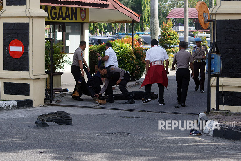 Petugas kepolisian mengevakuasi dua jenazah pelaku penyerangan di jalan pintu masuk Polda Riau di Pekanbaru, Riau, Rabu (16/5). 