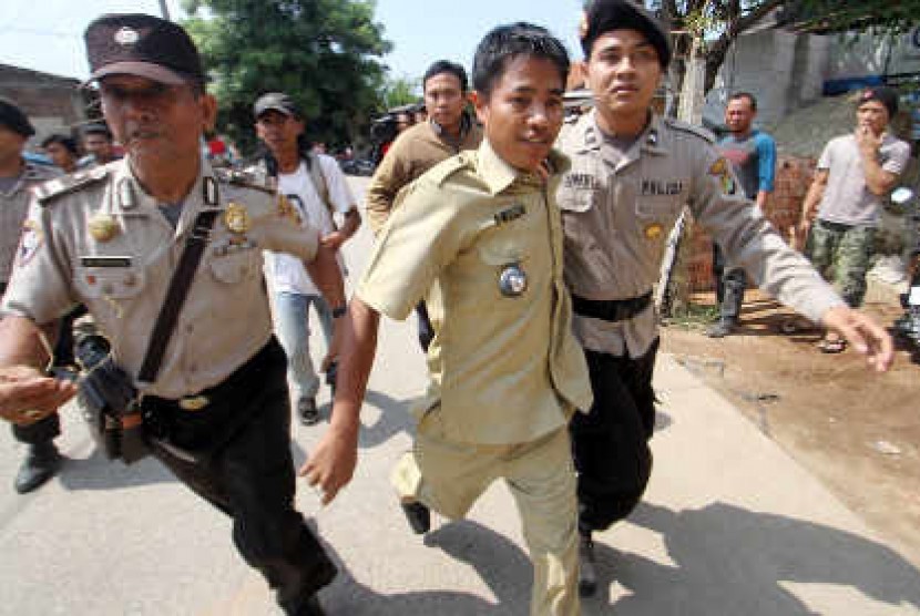 Petugas kepolisian mengevakuasi Kepala Desa Lebak Wangi Mursan (tengah) dari serangan warganya sendiri di Sepatan, Tangerang, Selasa (7/5). Warga menduga Musran mengetahui perbudakan buruh di pabrik panci milik kakak iparnya