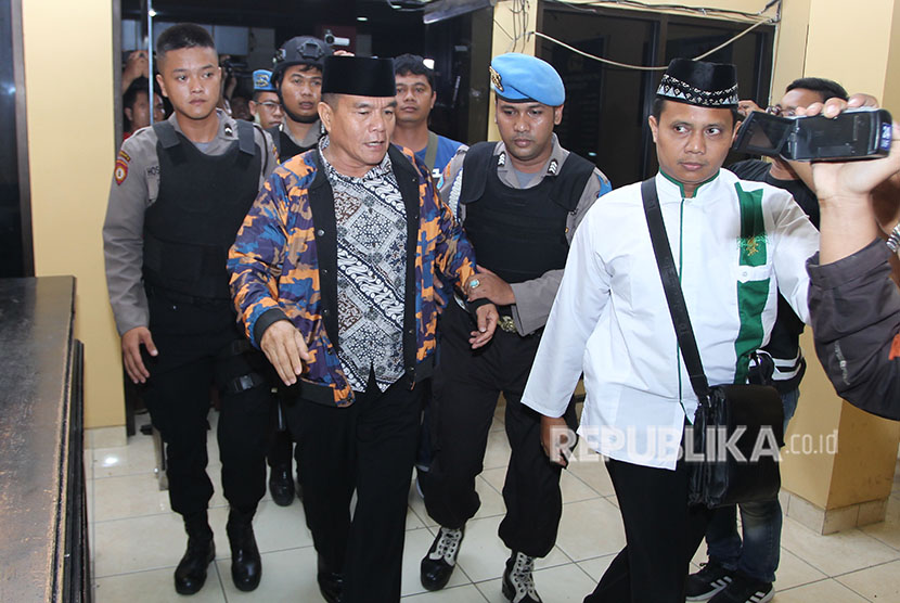 Petugas kepolisian menggiring Bupati Bengkulu Selatan Dirwan Mahmud (kedua kiri) yang terjaring Operasi Tangkap Tangan (OTT) oleh Komisi Pemberantasan Korupsi (KPK) saat tiba di Polda Bengkulu, Bengkulu, Selasa (15/5). 