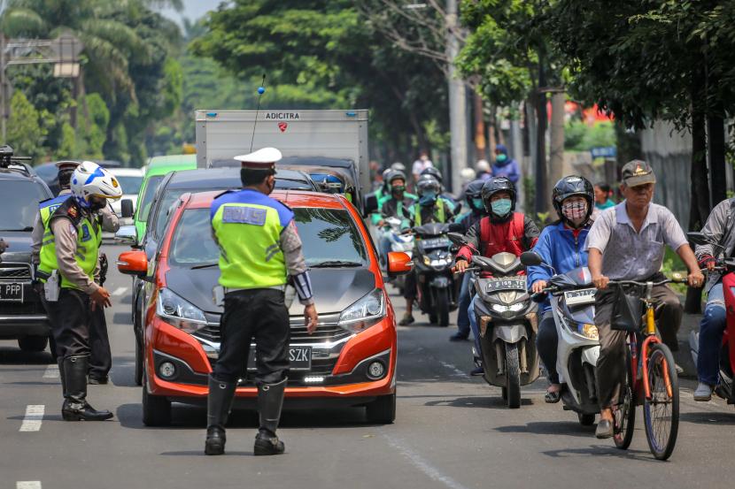 Petugas kepolisian menghentikan kendaraan yang melintas di perbatasan Tangerang-Jakarta di Jalan Daan Mogot, Jakarta, Jumat (10/4/2020). Polisi mengingatkan pengendara untuk selalu menggunakan masker dan aturan penumpang sesuai regulasi Pembatasan Sosial Berskala Besar (PSBB) di DKI Jakarta. 