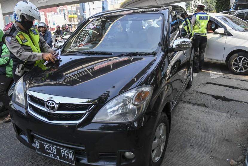Petugas kepolisian menghentikan mobil berplat nomor genap yang memasuki Jalan Salemba Raya, di Matraman, Jakarta, Senin (9/9/2019). Petugas kepolisian mulai memberlakukan penindakan berupa tilang terhadap pengendara mobil yang melanggar di kawasan perluasan sistem ganjil-genap. 