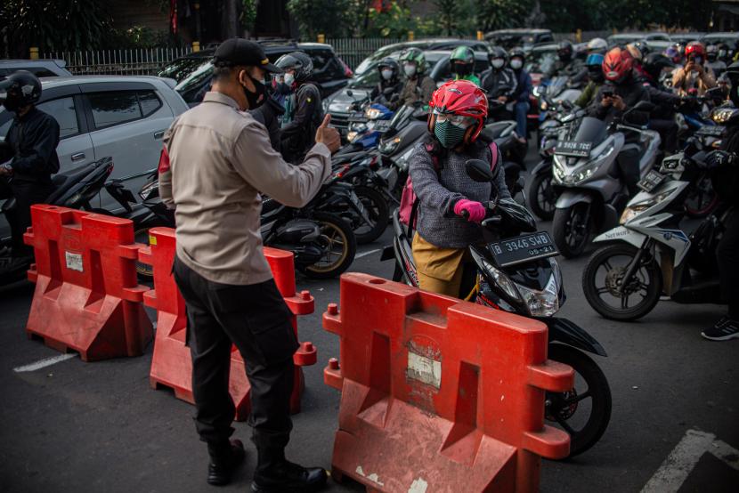 Petugas kepolisian mengimbau pengendara untuk memutar balik saat melewati posko penyekatan pada jam berangkat kerja di Jalan Lenteng Agung, Jakarta Selatan.