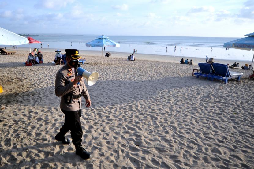 Petugas kepolisian mengimbau wisatawan untuk selalu menerapkan protokol kesehatan di Pantai Kuta, Badung, Bali, Jumat (14/5/2021). Petugas gabungan terus melakukan pengawasan penerapan protokol kesehatan untuk mencegah penyebaran COVID-19 terhadap wisatawan yang berlibur selama masa liburan Hari Raya Idul Fitri 1442 Hijriah di berbagai titik destinasi wisata Bali.