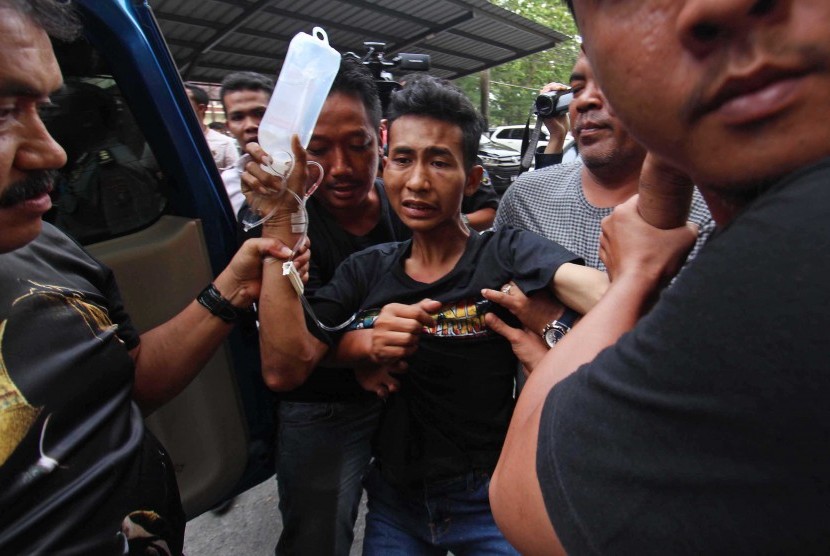 Petugas kepolisian mengiring seorang tersangka bernama Roni (21) yang berhasil ditangkap terkait kasus pembunuhan sekeluarga saat tiba di Mapolda Sumatera Utara, Medan, Rabu (12/4).