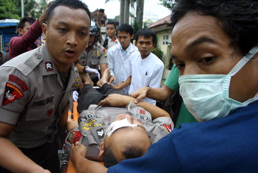  Petugas kepolisian menolong polisi yang menjadi korban bentrok antara mahasiswa dan polisi pada aksi demonstrasi di Kampus Universitas Pamulang, Pamulang, Tangerang Selatan, Kamis (19/10).   (Muhammad Iqbal/Antara)