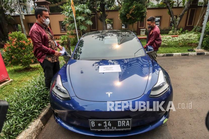 Petugas kepolisian menunjukkan barang bukti berupa mobil Tesla Model 3 saat gelar barang bukti kasus afiliator Binomo dengan tersangka Indra Kesuma atau Indra Kenz di Bareskrim, Mabes Polri, Jakarta, Jumat (25/3/2022). Dalam acara tersebut petugas kepolisian menghadirkan sejumlah barang bukti berupa uang sejumlah Rp1,24 miliar serta mobil Tesla Model 3. 