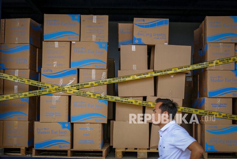 Petugas kepolisian Polda Metro Jaya melintasi barang bukti saat rilis dugaan penimbunan masker di gudang di Neglasari, Kota Tangerang, Banten.(Antara/Fauzan)