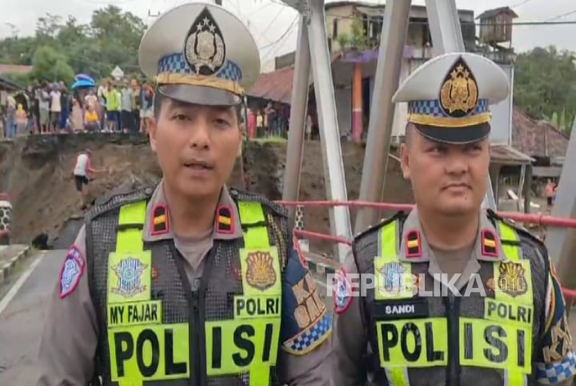 Petugas kepolisian Polres Sukabumi tengah mengecek kondisi Jembatan Bojongkopo yang mengarah ke Palabuhanratu terputus akibat tergerus arus air Sungai Cidadap, Jumat (7/3/2025). 