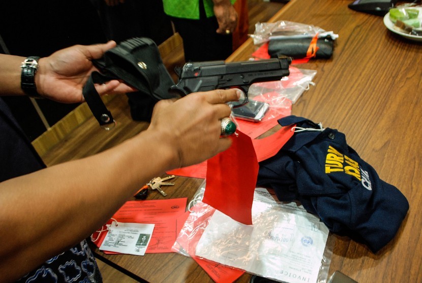 Petugas kepolisian memperlihatkan barang bukti senjata api mainan milik seorang tersangka.