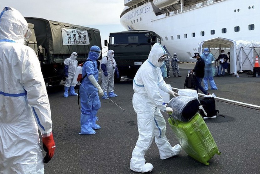 Petugas kesehatan bersiap menyemprotkan cairan disinfektan kepada WNI ABK Diamond Princess dan barang bawaan saat turun dari kapal di Yokohama, Jepang, Minggu (2/3/2020). Pemerintah mengevakuasi 69 WNI ABK Diamond Princess yang dinyatakan negatif COVID-19 untuk dipulangkan ke tanah air dan diobservasi di pulau Sebaru Kecil, Kepulauan Seribu.