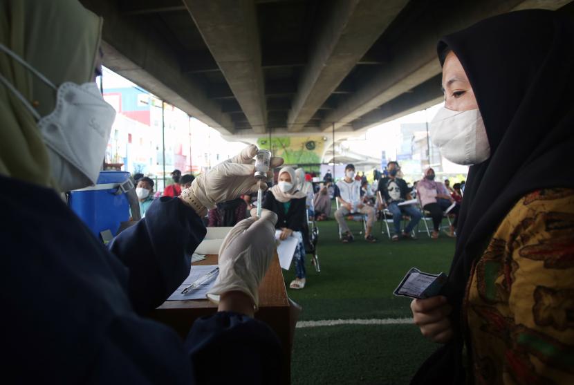 Petugas kesehatan bersiap menyuntikan vaksin booster COVID-19 ke seorang warga di bawah jembatan layang Ciputat, Tangerang Selatan, Banten, Sabtu (2/4/2022). Vaksinasi yang diselenggarakan Polri diikuti warga sekitar dan pedagang Ciputat yang berencana akan mudik lebaran.
