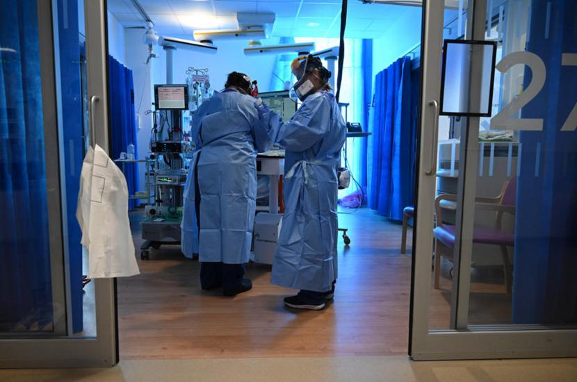  Petugas kesehatan memakai Alat Pelindung Diri (APD) saat merawat pasien di unit Perawatan Intensif di Rumah Sakit Royal Papworth di Cambridge, Inggris (ilustrasi). Inggris mengoperasikan kembali rumah sakit darurat yang dibangun pada awal pandemi dan menutup sekolah dasar di London pada Jumat (1/1/2021). EPA-EFE / NEIL HALL / POOL