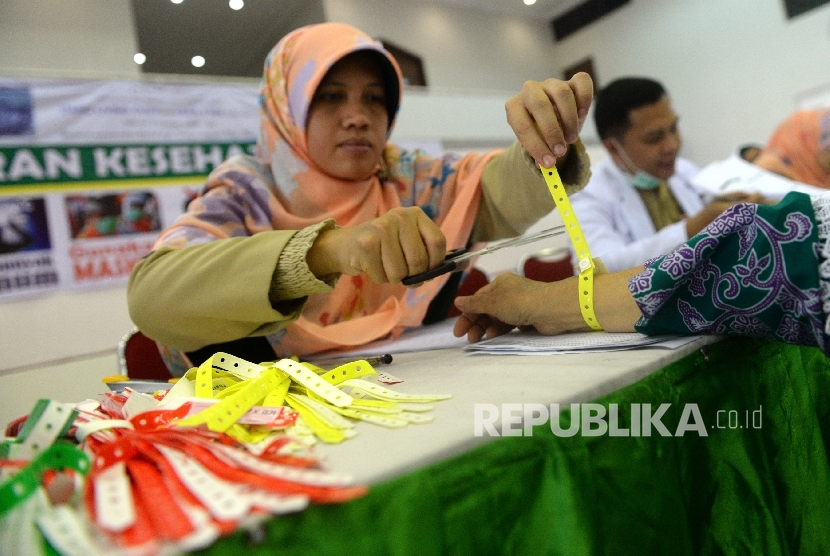 Petugas kesehatan memasang gelang kepada jamaah calon haji.