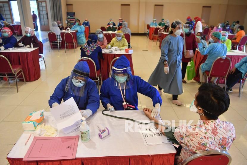 Petugas kesehatan memeriksa kesehatan penerima vaksin COVID-19 saat pelaksanaan vaksinasi massal di Surabaya, Jawa Timur, Minggu (31/1/2021). Vaksinasi massal tersebut diikuti kurang lebih 5.000 tenaga kesehatan. 