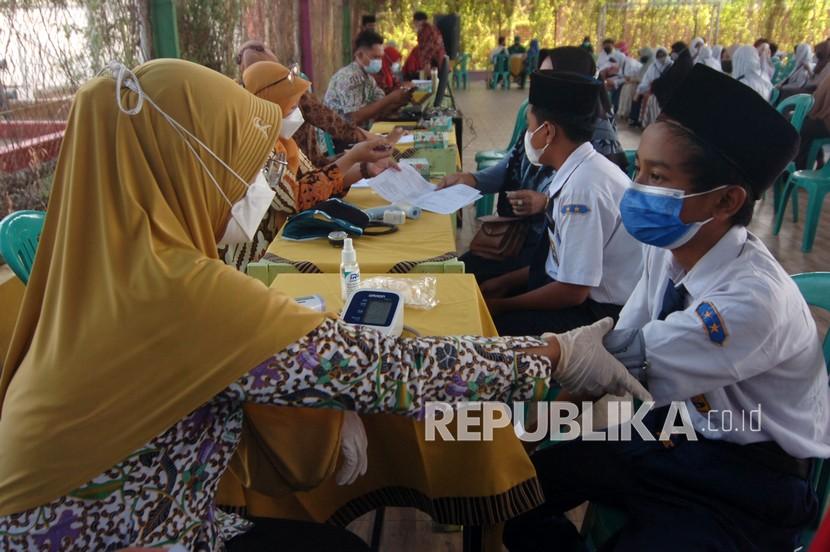 Petugas kesehatan memeriksa kesehatan sebelum menyuntikkan vaksin COVID-19 kepada pelajar di SMP Ihsaniyah Kota Tegal, Jawa Tengah, Selasa (31/8/2021). Vaksinasi COVID-19 tersebut guna persiapan pembelajaran tatap muka guna membentuk kekebalan komunal serta meningkatkan capaian vaksinasi. 