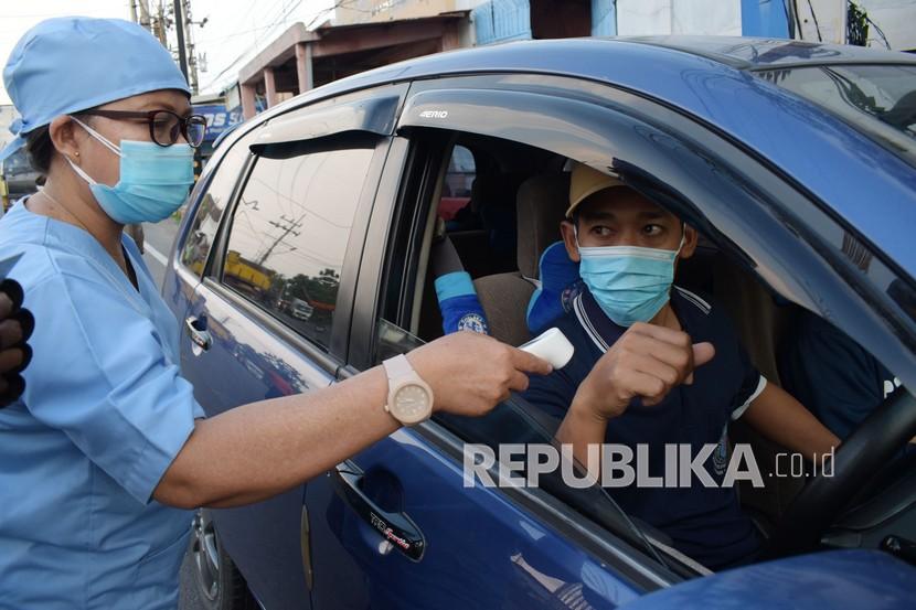 Petugas kesehatan memeriksa suhu tubuh pengendara saat penyekatan dalam rangka larangan mudik di Kota Madiun, Jawa Timur, Jumat (30/4/2021). Penyekatan yang dilakukan petugas gabungan TNI, Polri, Satpol PP, Badan Penanggulanan Bencana Daerah (BPBD) dan Dinas Kesehatan dimaksudkan untuk mengantisipasi pemudik masuk wilayah Kota Madiun guna pencegahan penularan COVID-19. 