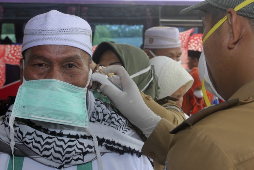  Petugas kesehatan memeriksa suhu tubuh seorang haji dengan alat pengukur saat kedatangan jamaah haji di Asrama Haji Provinsi Bengkulu. 387 Jamaah Haji Bengkulu Tiba di Asrama Haji 