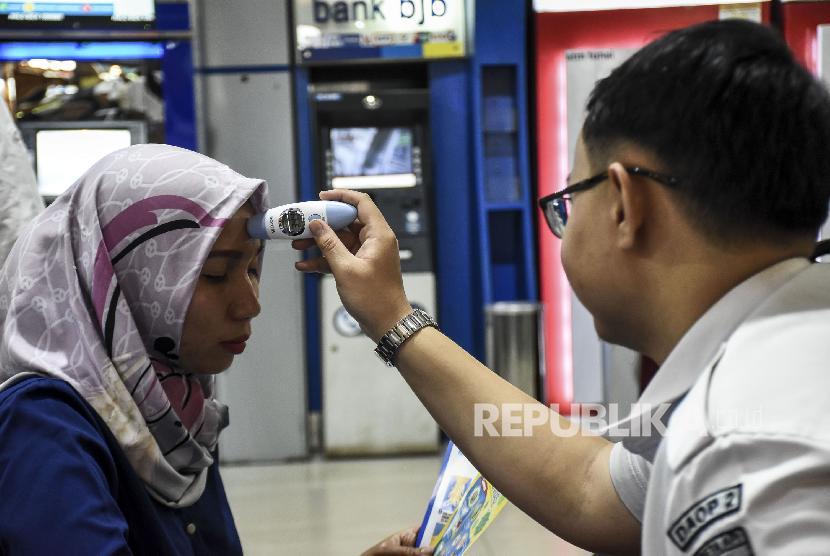 Petugas Kesehatan mengecek suhu tubuh calon penumpang menggunakan alat thermo gun di Stasiun Bandung, Kota Bandung, Kamis (5/3).(Republika/Abdan Syakura)