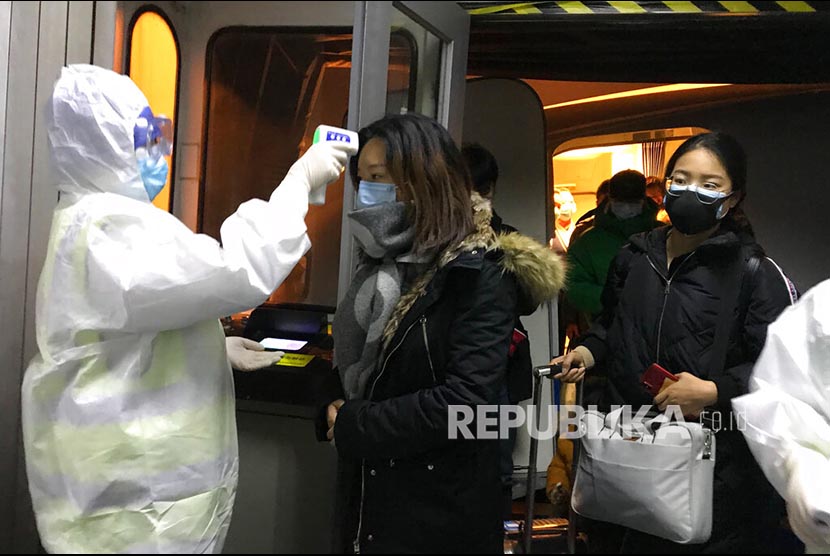 Petugas kesehatan mengenakan pakaian anti bahan berbahaya (hazardous material suit) memerilksa suhu tubuh penumpang yang datang dari daerah Wuhan di  Bandara Beijing, China.  Wabah Virus Wuhan di China telah memakan korban 17 orang meninggal dan ratusan lainnya positif terjangkit.
