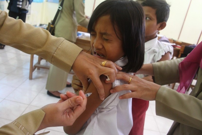 Petugas kesehatan menyuntikan Difteri Tetanus (DT) kepada seorang pelajar SD ketika proses imunisasi DT di SDN Torongrejo 2, Batu, Jawa Timur.
